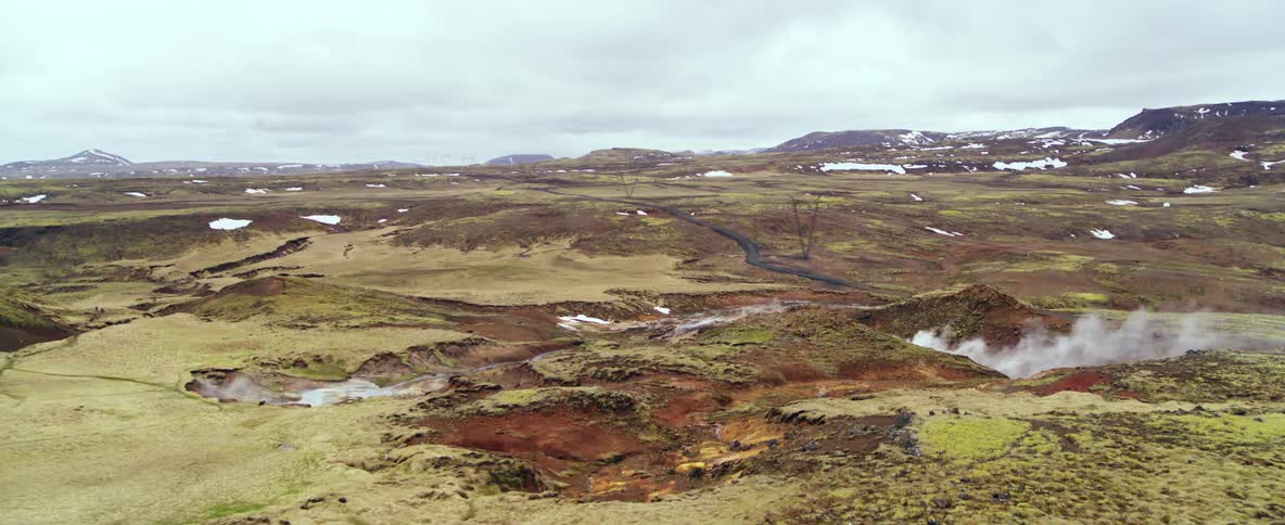 Steam is rising from hot springs in a natural landscape on a cold day