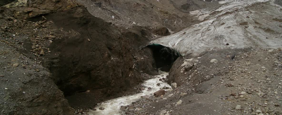 A rocky hillside has a small waterfall running through it