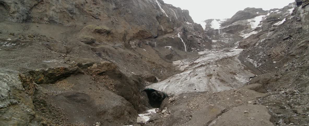 Streams of water from a glacier trickle down a mountainside during the day