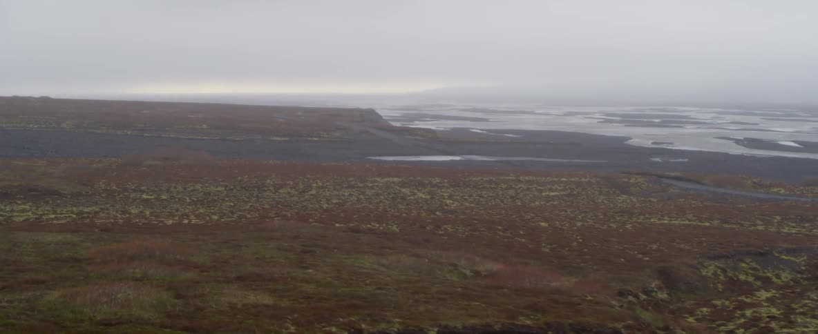 The waves crash against the rocks of the foggy shore