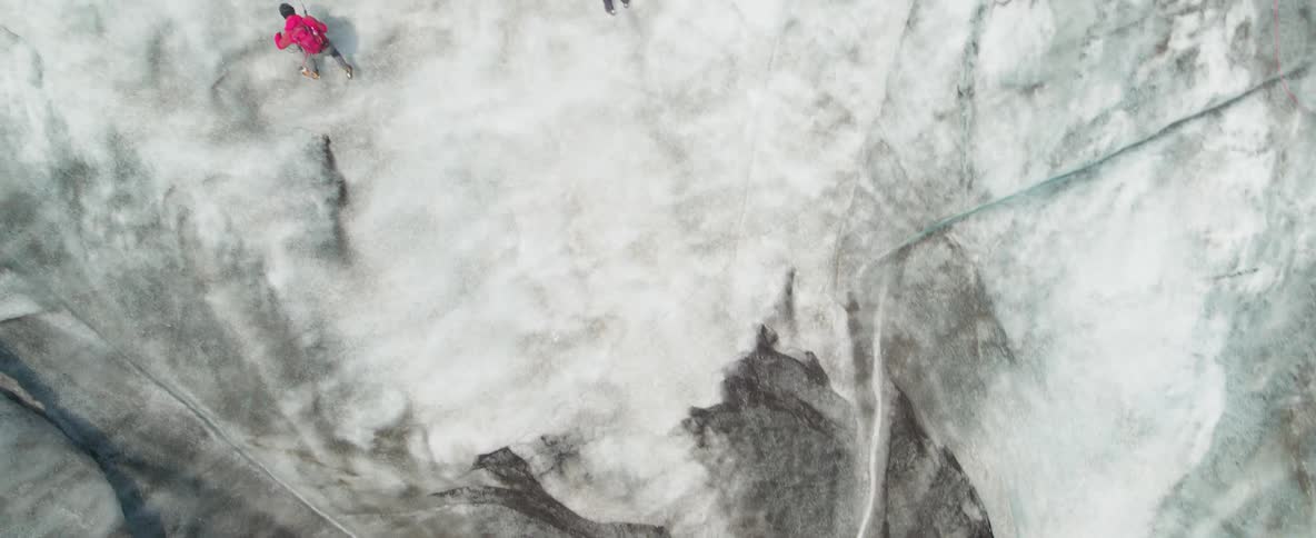 Two climbers are scaling a glacier wall during the day