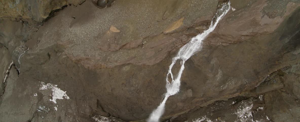 A stream of water is flowing over a cliff during the day