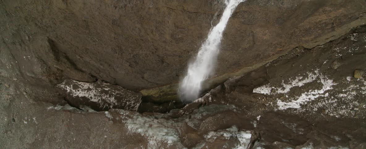 Water flows rapidly down a stream off a cliff