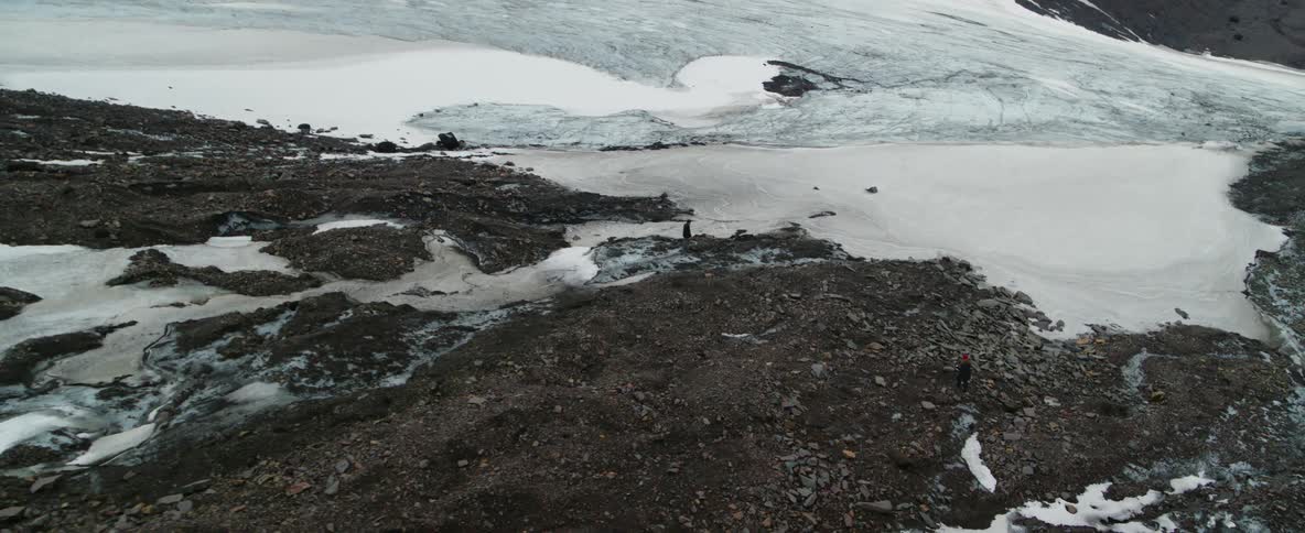 A man stands at the edge of frozen water