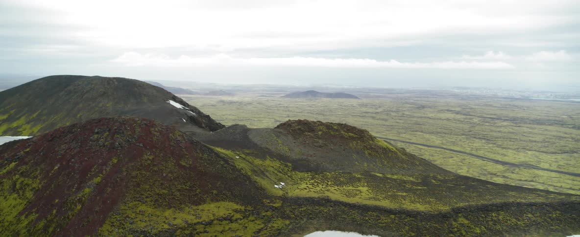 The tall mountains are covered with green grass and snow