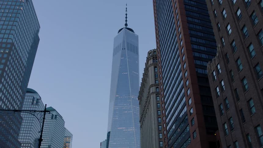 A tall skyscraper towers above a city at dawn