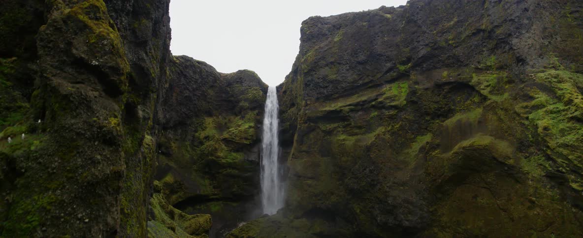 A waterfall flows over a mossy cliffside