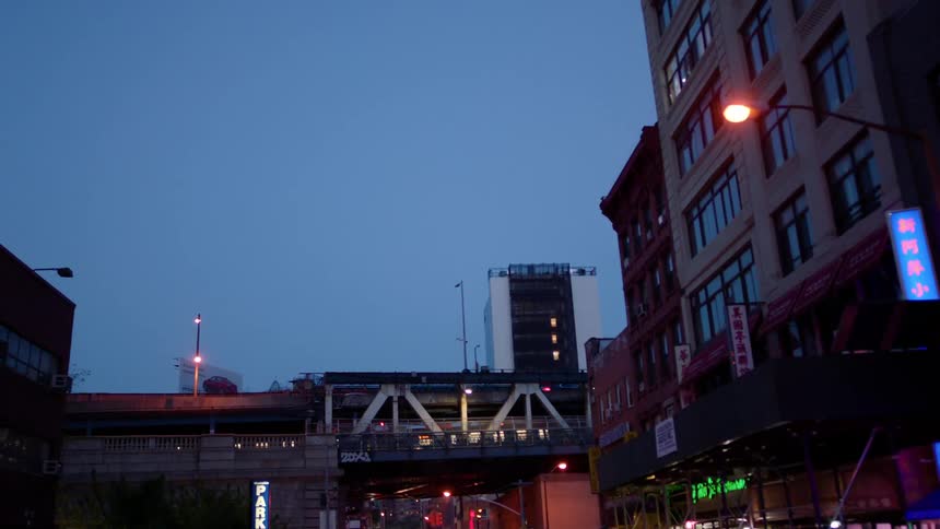 A train travels over a city bridge at night