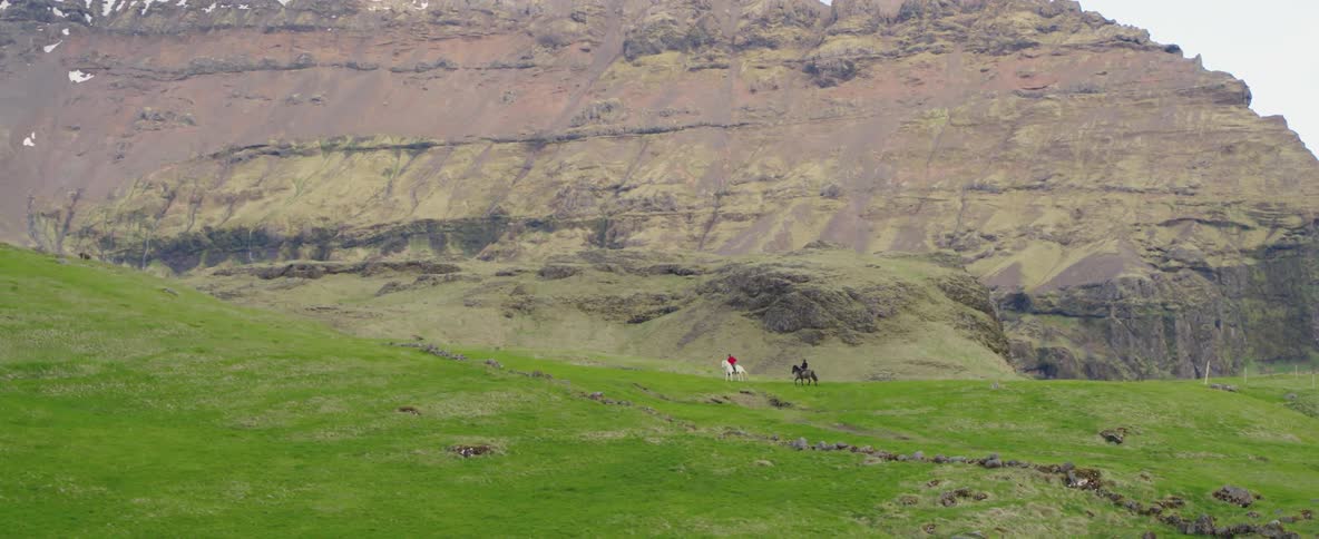 Two people go horseback riding in the mountains