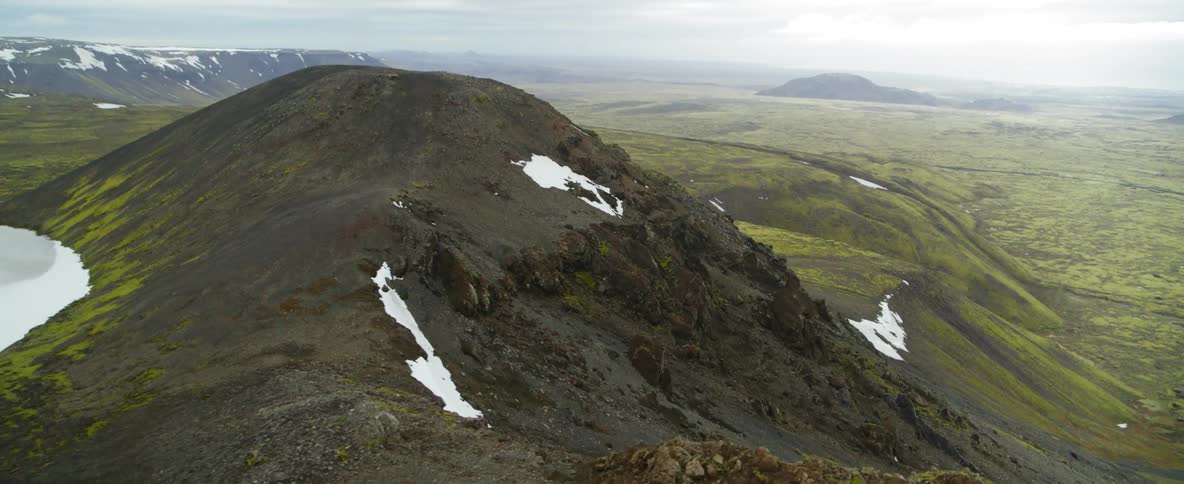 A mossy mountain with patches of snow