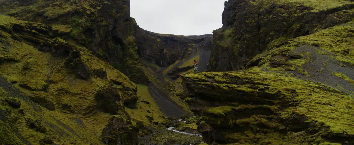 A hiker stands on a cliff in the mountains