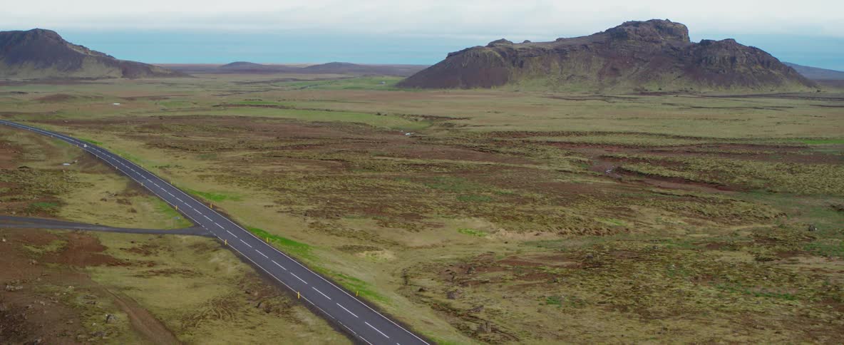A two lane road stretches across a natural landscape on a cloudy day