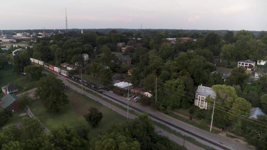 The train is passing through the town on a cloudy day