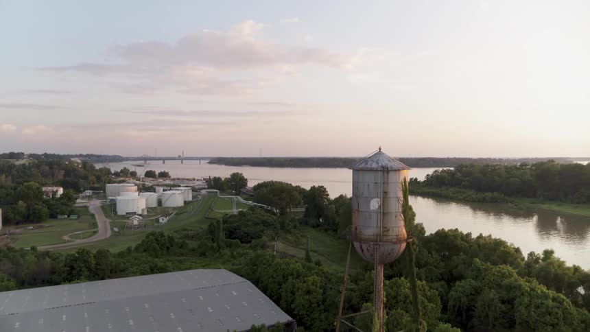 A water tower stands tall above industrial buildings