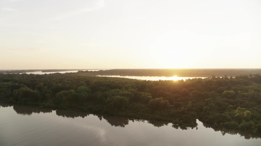 The sun is gleaming off of wetlands near an agribusiness operation at dawn