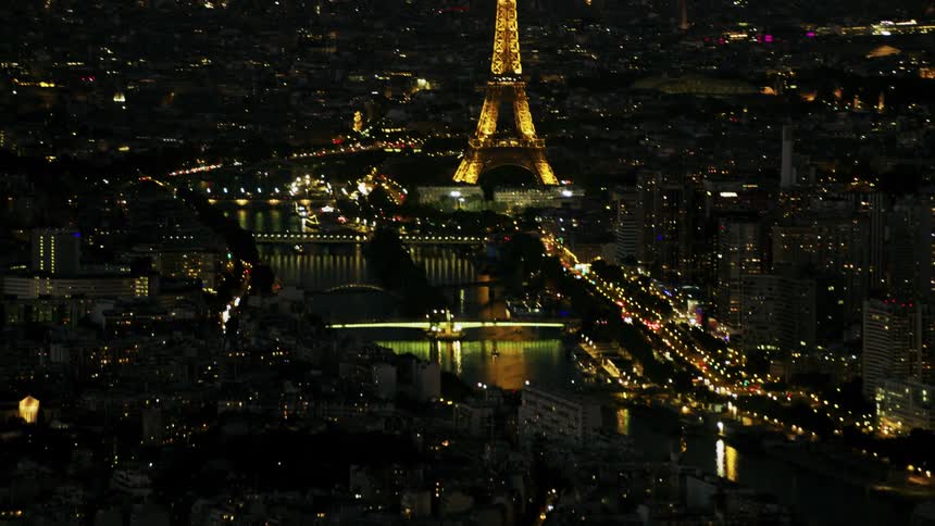 Traffic flows on city streets near the eiffel tower at night