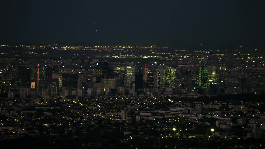 Lights glimmer in a city and surrounding area at night