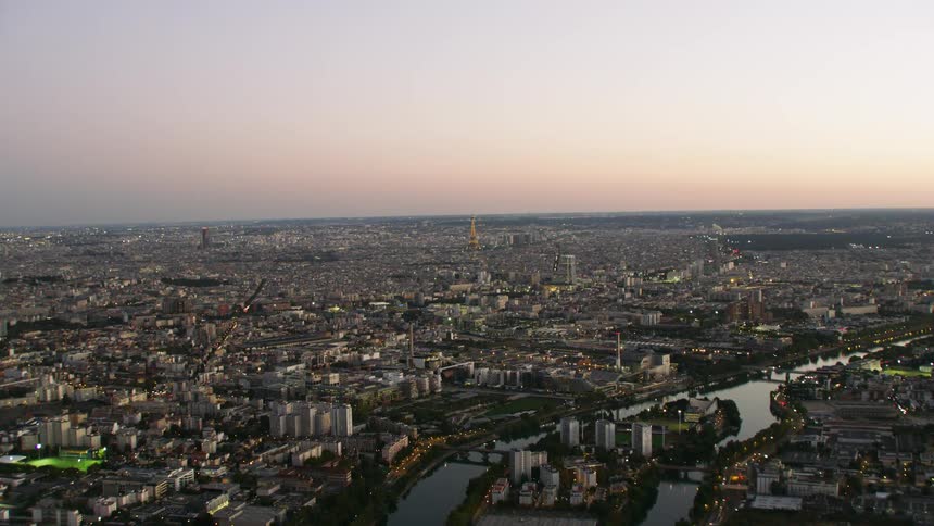 City buildings illuminate the dusk sky