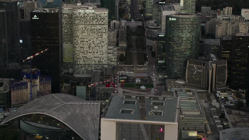 Lights illuminate the  architecture of buildings in a city at dusk