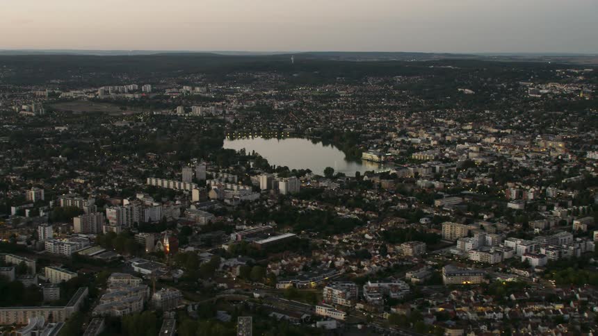 Lac d'Enghien is surrounded by city buildings at sunset