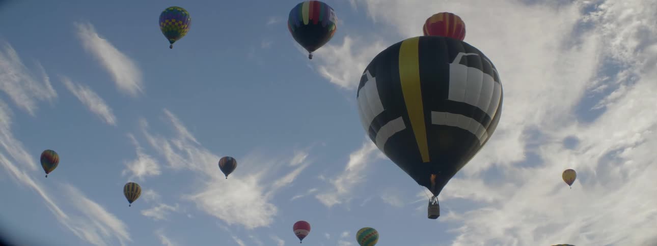 Hot air balloons are floating in a cloudy sky during the day