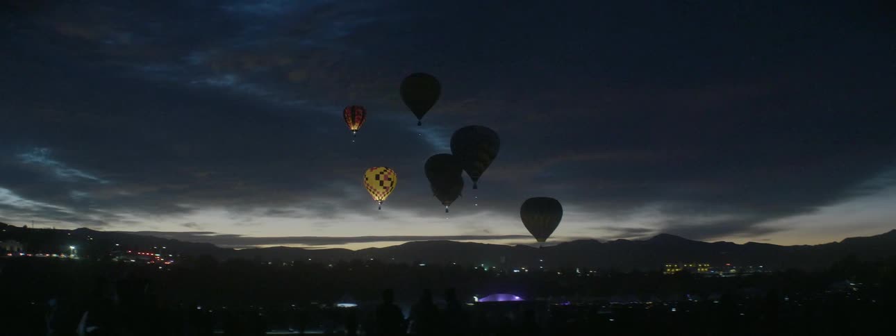 Hot air balloons flicker in the night sky