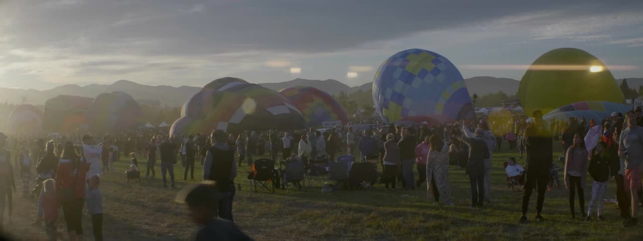 Crowds spectate as hot air balloons are prepared for flight