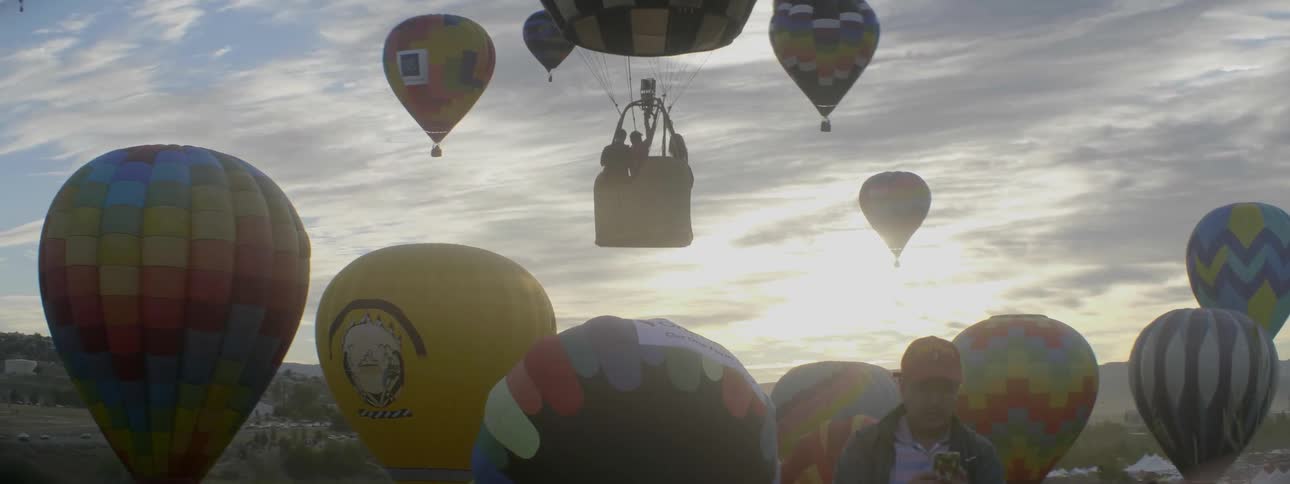 A hot air balloon carries passengers as it rises into the sky at dusk
