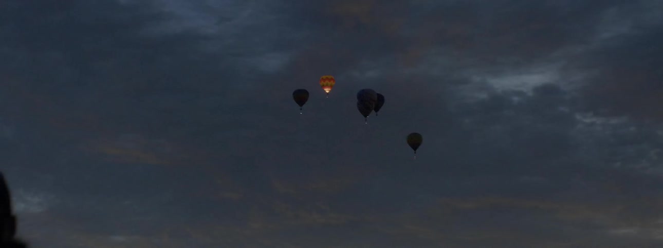 Hot air balloons glow in the night sky
