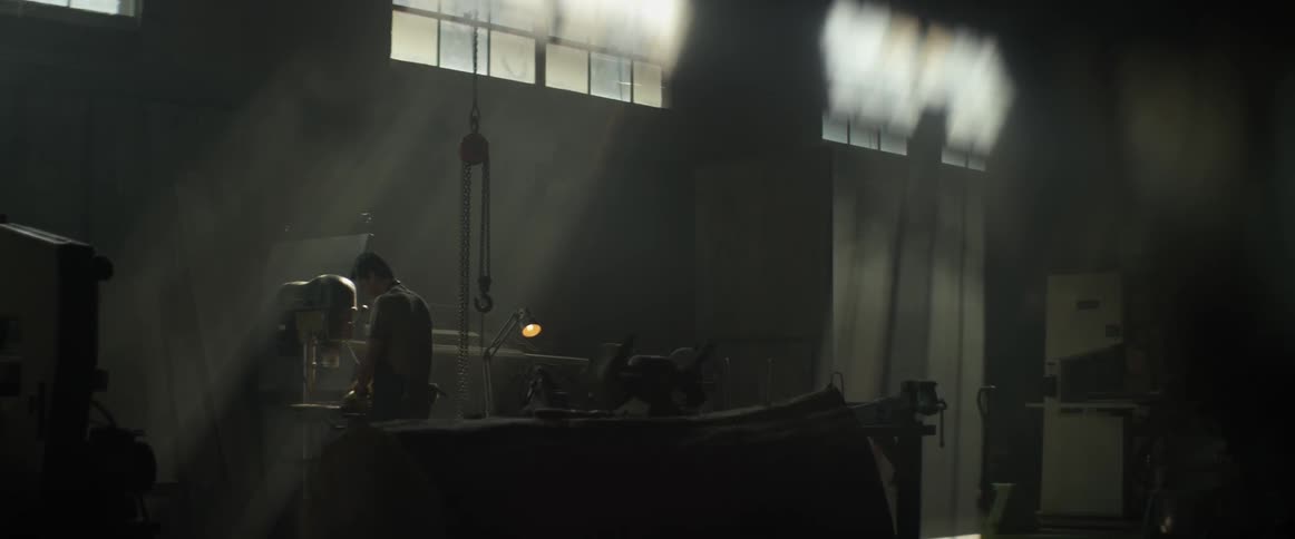A man is standing at a piece of machinery in his workshop