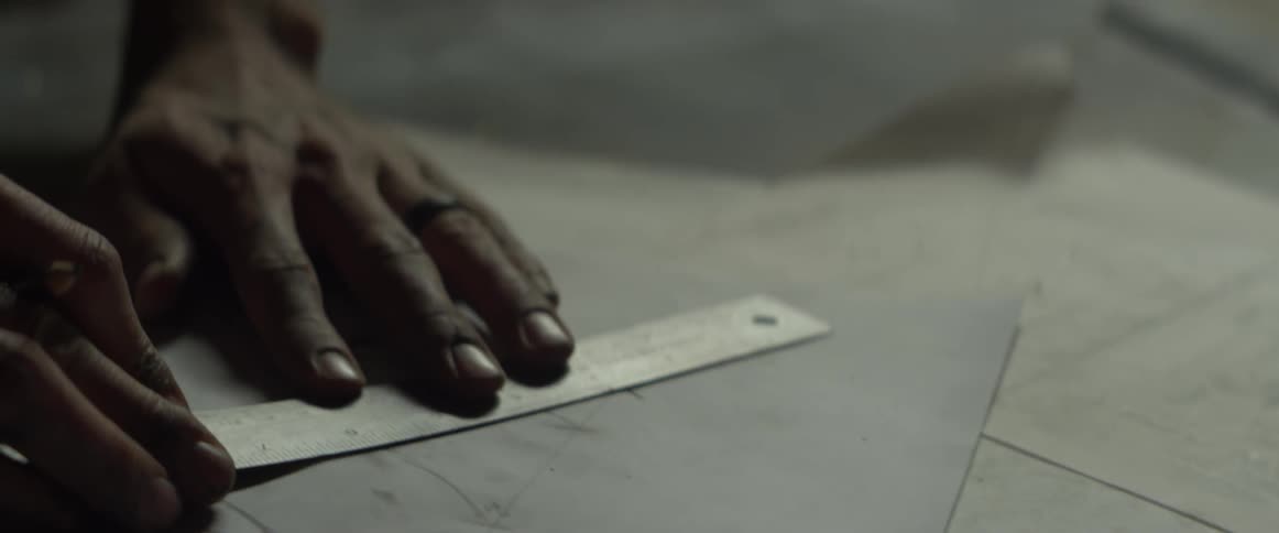 A man draws lines with a metal ruler