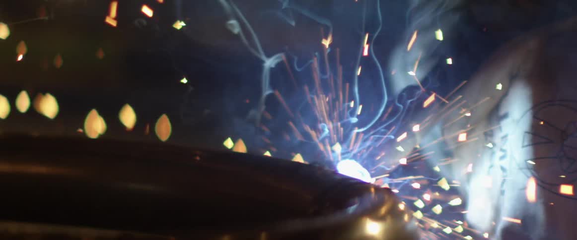 Sparks fly as a man welds a pipe