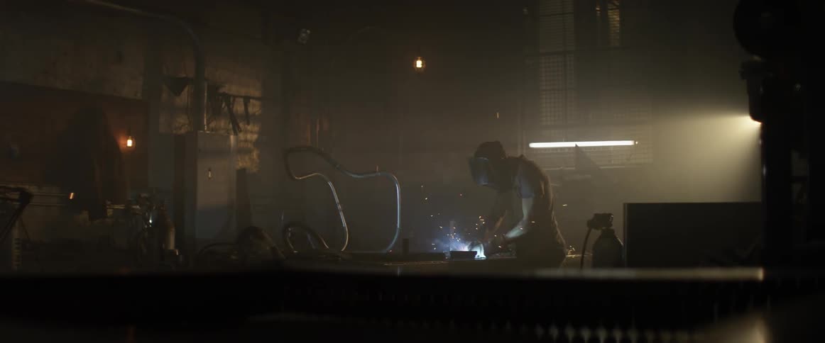 Sparks fly around a welder in a workshop