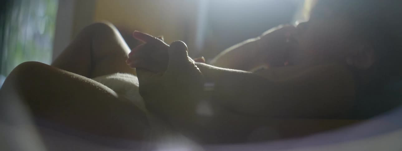 Person holds an infant in their lap and plays with the infant's hand
