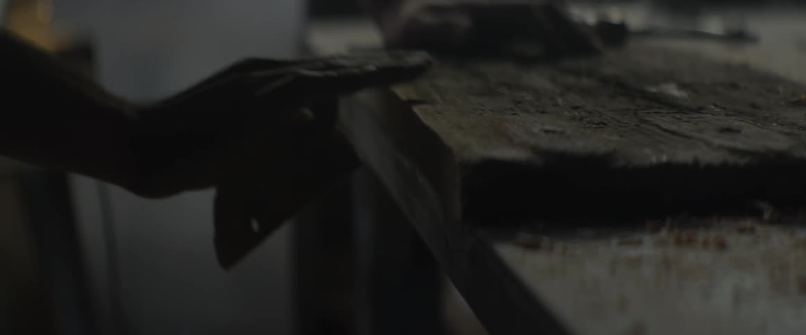 A man sands wood in a workshop