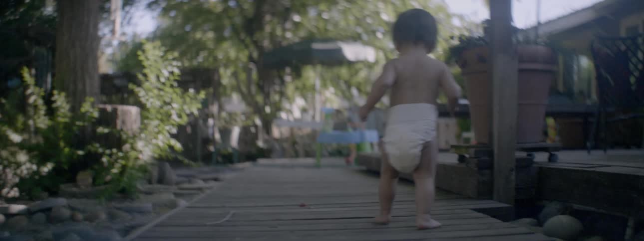A toddler is exploring a backyard on a sunny day