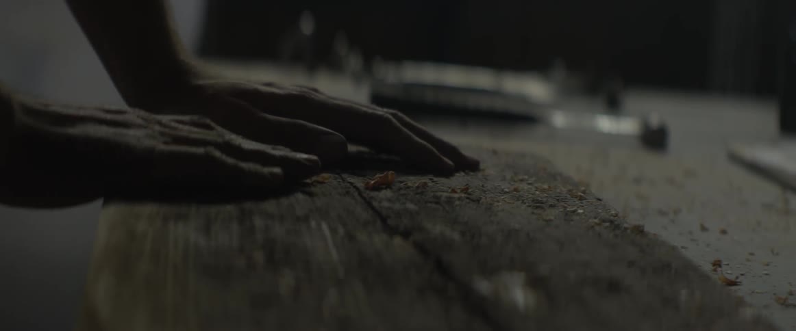 A man rubs a piece of wood on a table in a workshop