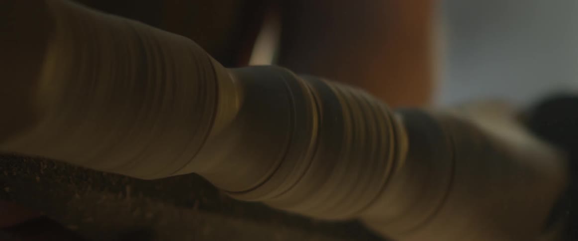 A man shapes a piece of wood on a lathe