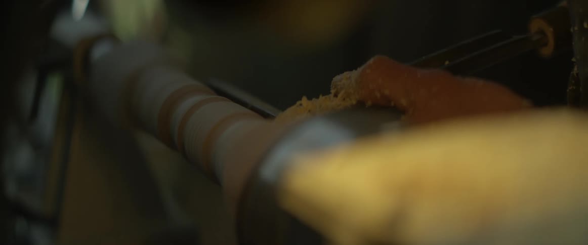 A man shapes a piece of wood on a lathe