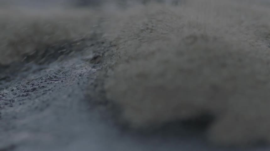 Sand falls onto black liquid