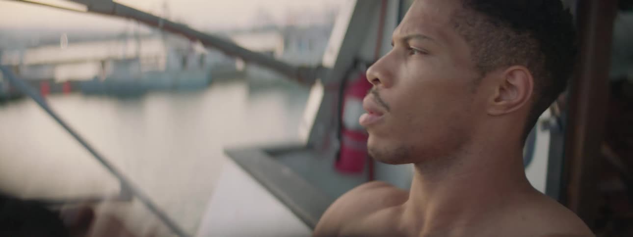 A shirtless man exits a boat cabin