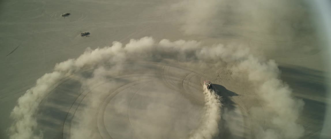A man rides on a vehicle doing donuts in the desert