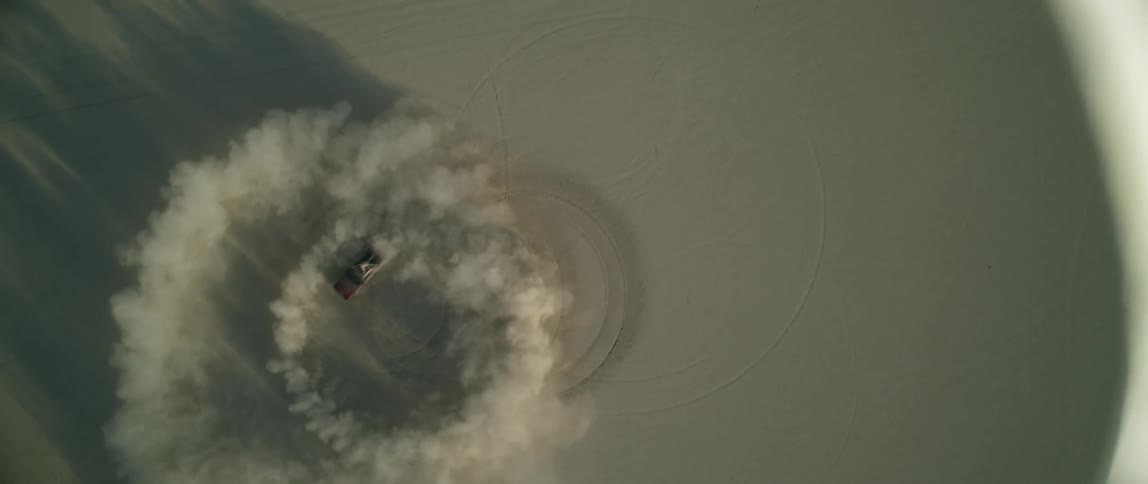 A person drives a truck in circles and stirs up dirt