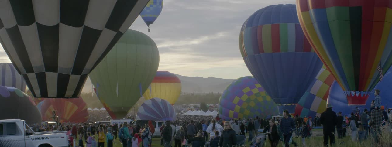 Groups of people gather near large hot air balloons