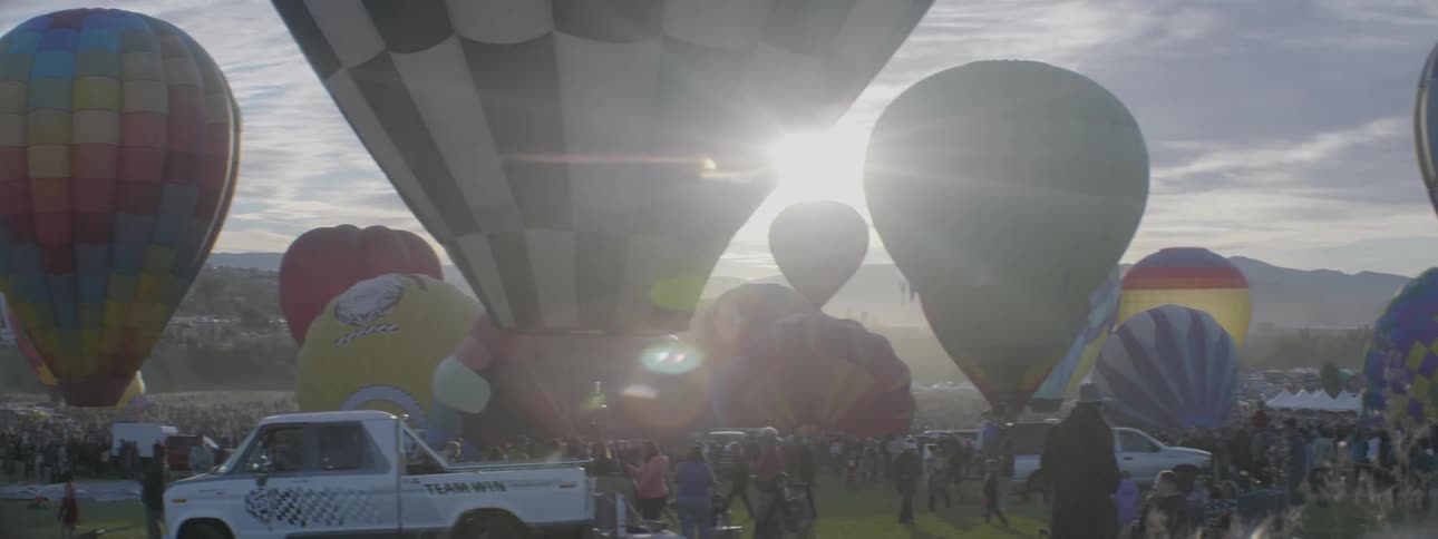 People walk by a large group of hot air balloons