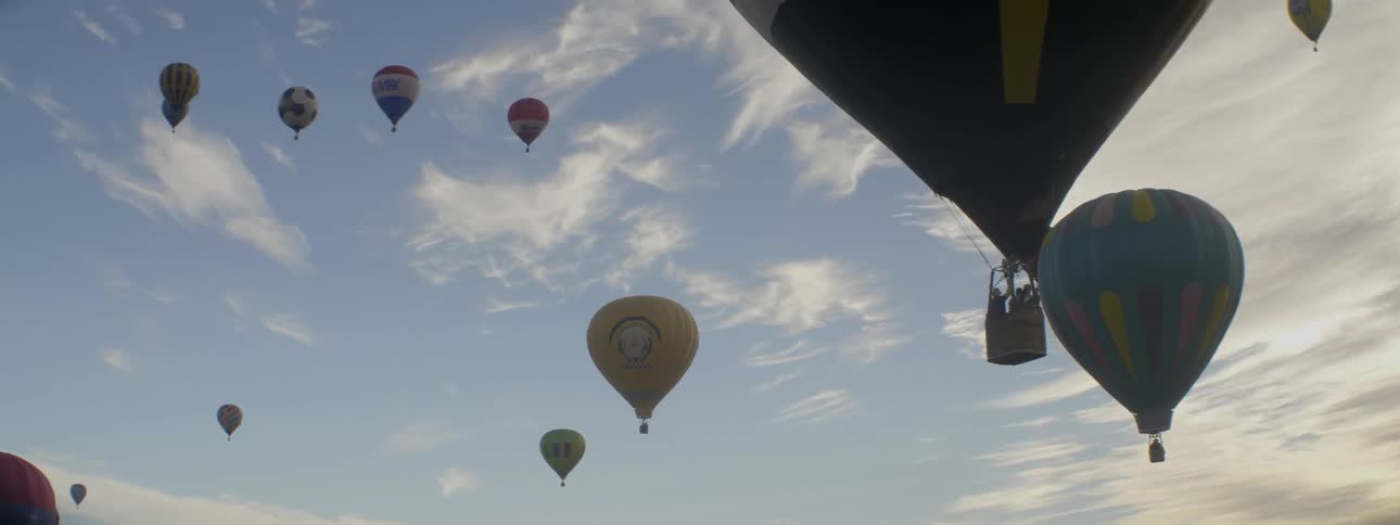 Hot air balloons rise into the sky and float during the day