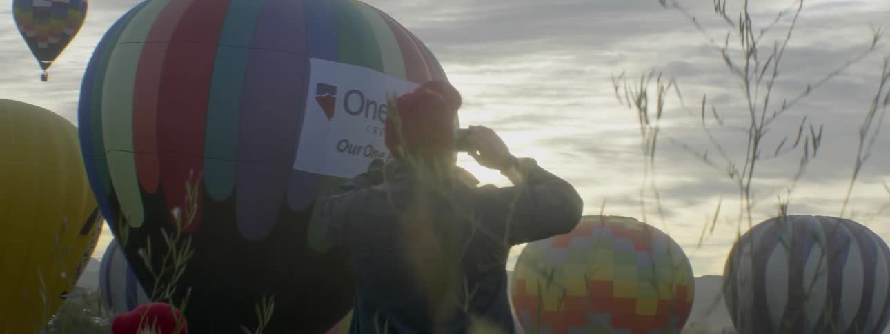 Man photographs hot air balloons at sunset