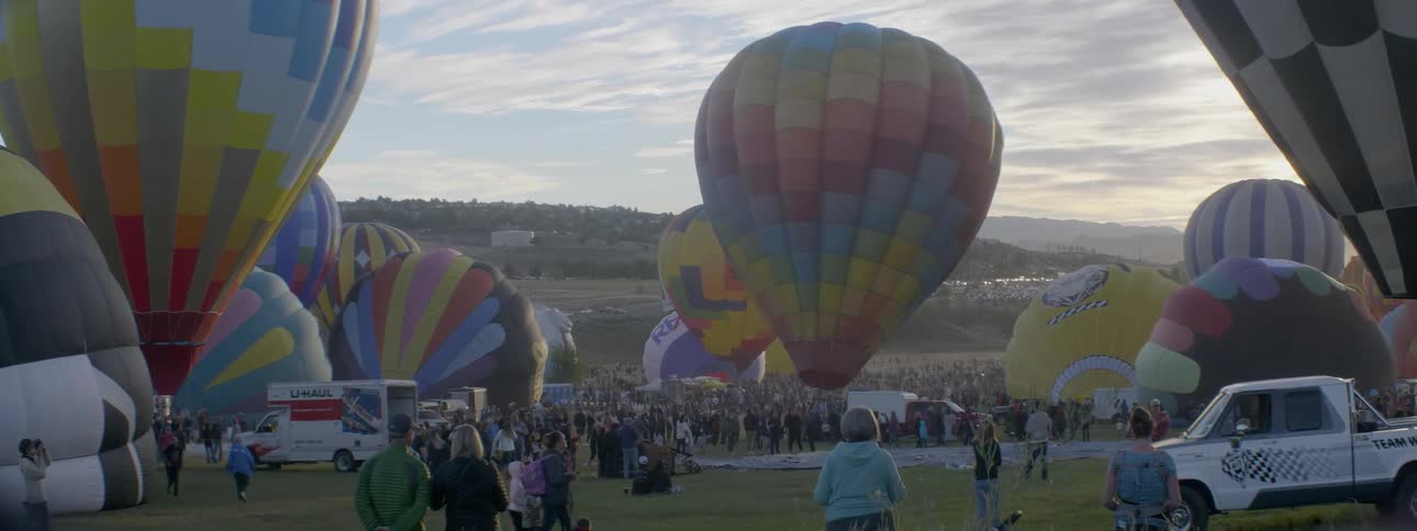 Crowds spectate as hot air balloons are prepared for flight