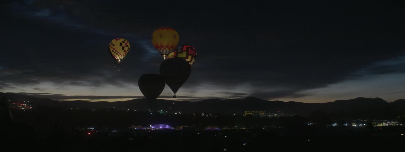 Hot air balloons flicker in the night sky