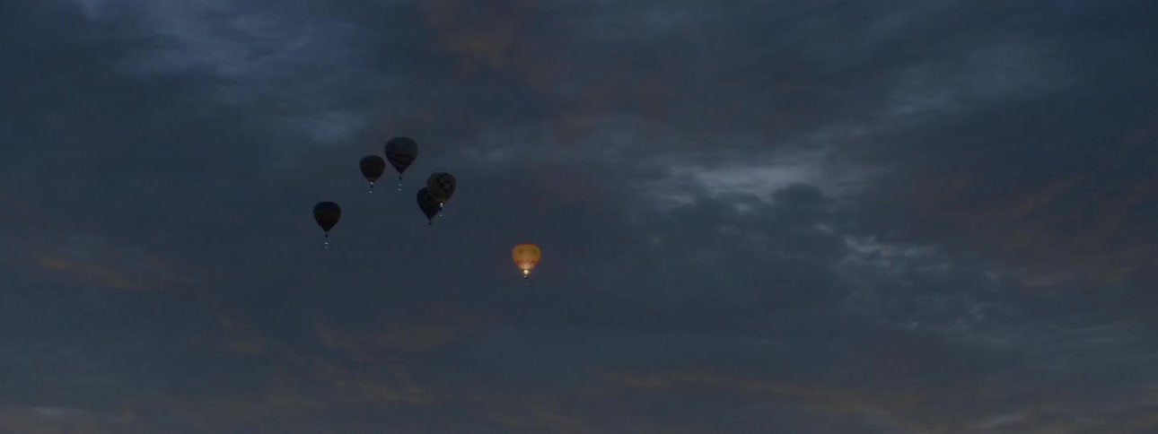Hot air balloons are rising high into the air at night